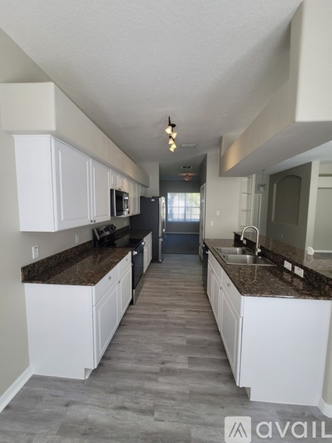 A kitchen with white cabinets and a granite countertop.