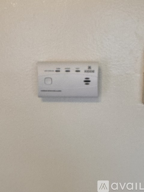A white thermostat on a beige wall.