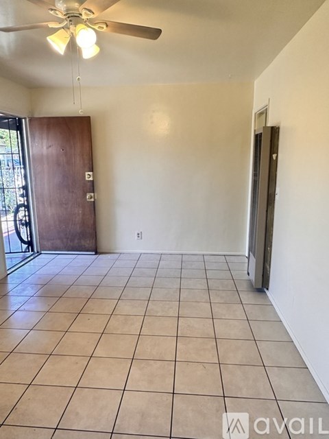 A room with a ceiling fan and tile flooring.