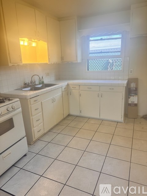 A kitchen with white cabinets and a white tiled floor.