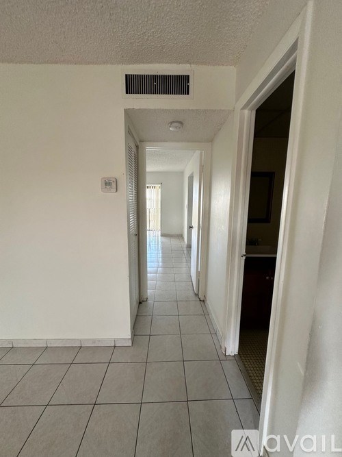 A long hallway with tiled floors and white walls.