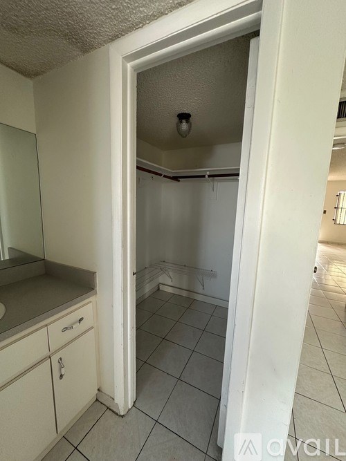 A white doorway opens to a small, empty room with a tiled floor.