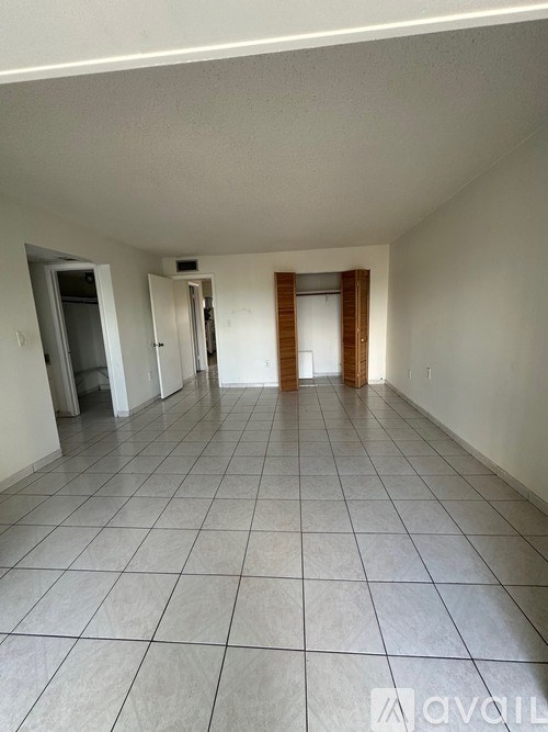 A spacious room with tiled flooring and white walls.