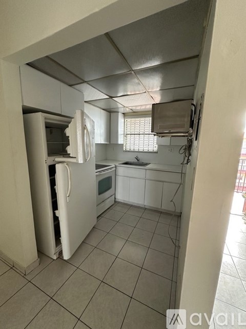A kitchen with a white fridge and white cabinets.