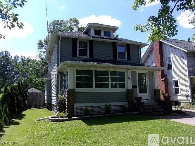 A house with a grey siding and a white door is for sale.