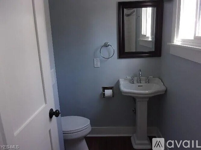 A bathroom with a toilet, sink, and mirror.