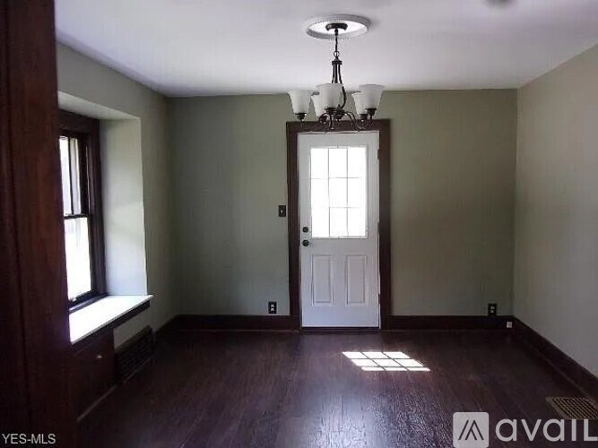 A room with a white door and a window on the left side.