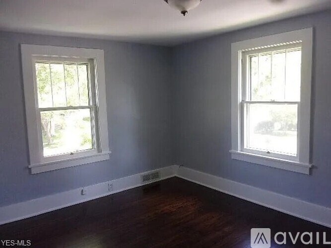 A room with two windows and wooden floors.