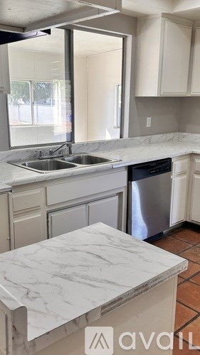 A kitchen with a marble countertop and a dishwasher.