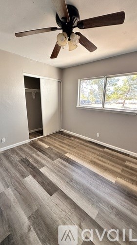 A room with a ceiling fan and wood flooring.