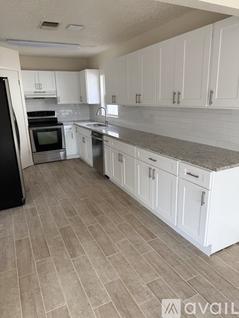 A kitchen with white cabinets and a black refrigerator.