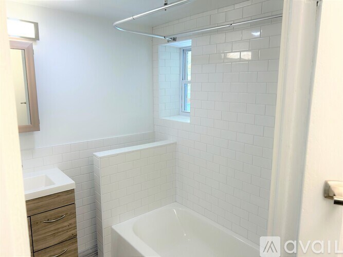 A white bathroom with a tub, sink, and mirror.