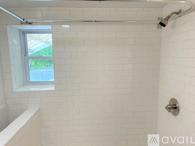 A white tiled bathroom with a window.