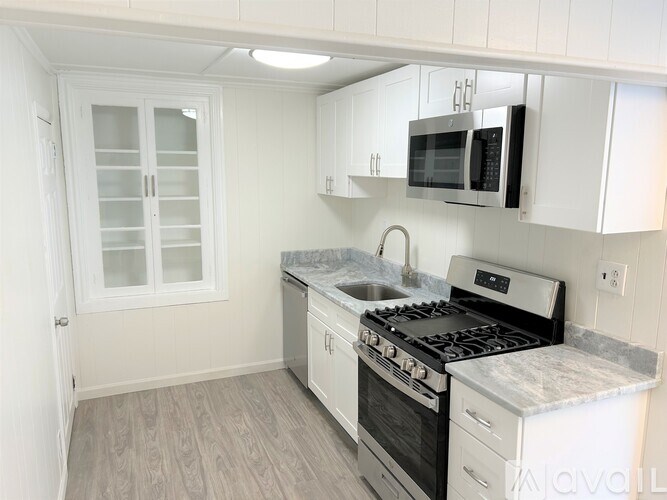 A kitchen with white cabinets and a marble countertop.