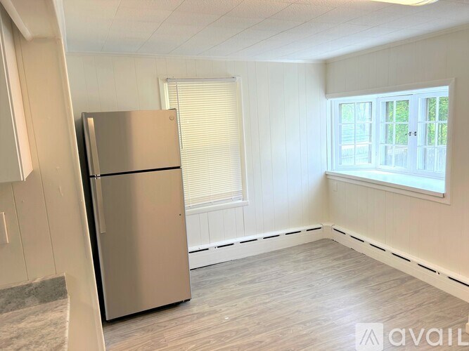 A modern kitchen with a stainless steel refrigerator and wooden flooring.