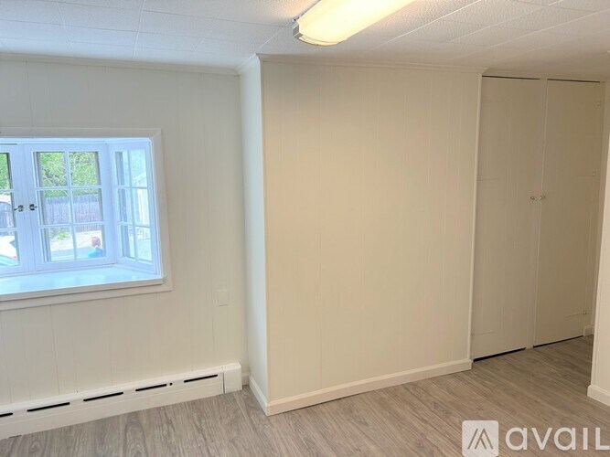 A room with a window and a door is available for rent.