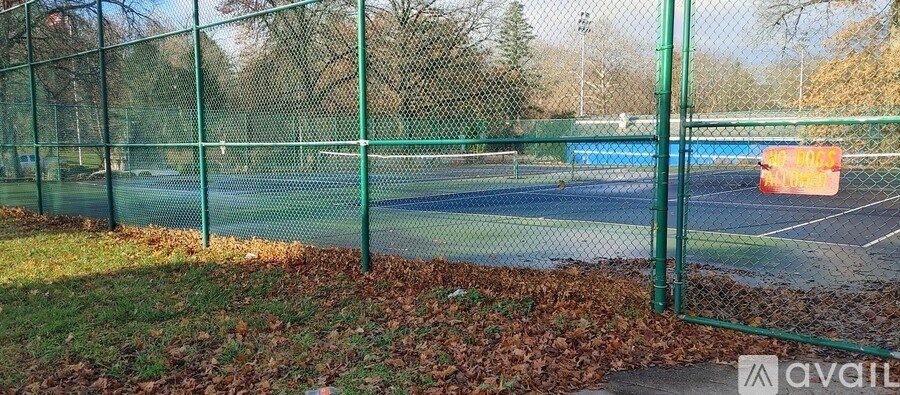 Tennis court surrounded by a green fence.