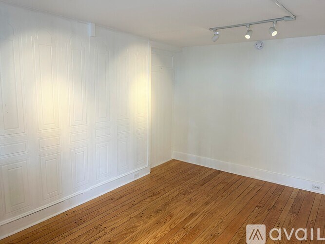 A room with wooden flooring and white walls.