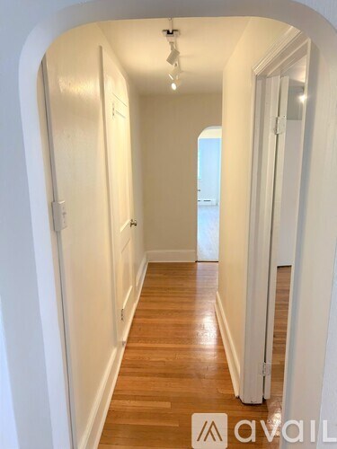 A hallway with wooden floors and white walls.