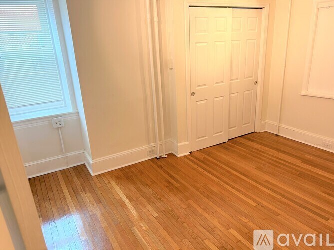 A room with a white door and wooden flooring.
