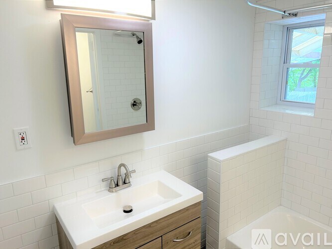 A bathroom with a sink, mirror, and a window.