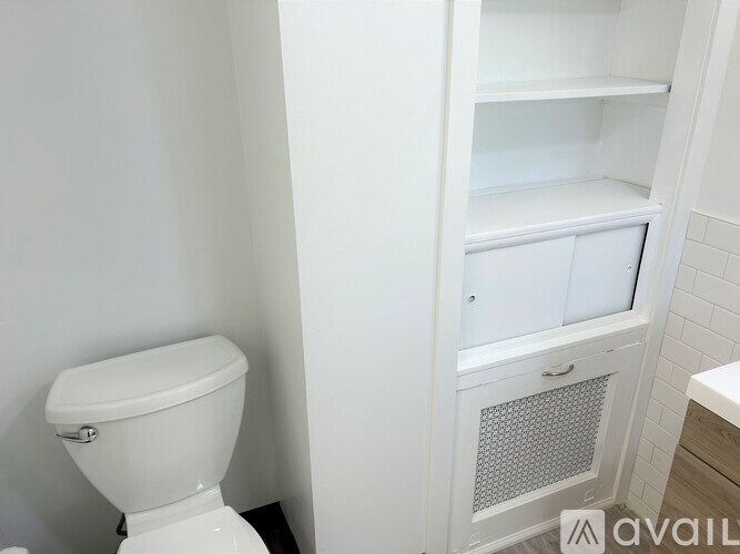A white toilet sits next to a white cabinet with a white sink.