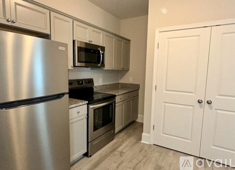 A kitchen with a stainless steel refrigerator, microwave, oven, and cabinets.