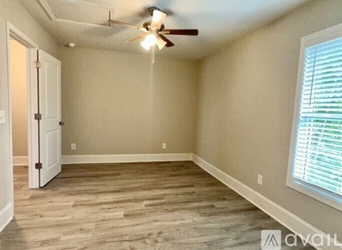 A room with a ceiling fan and a door.