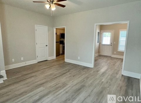 A room with a ceiling fan and wooden flooring.