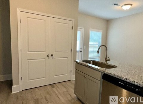 A kitchen with a sink, cabinets, and a door.