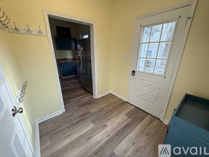 A room with a white door and a window with a view of a building outside.