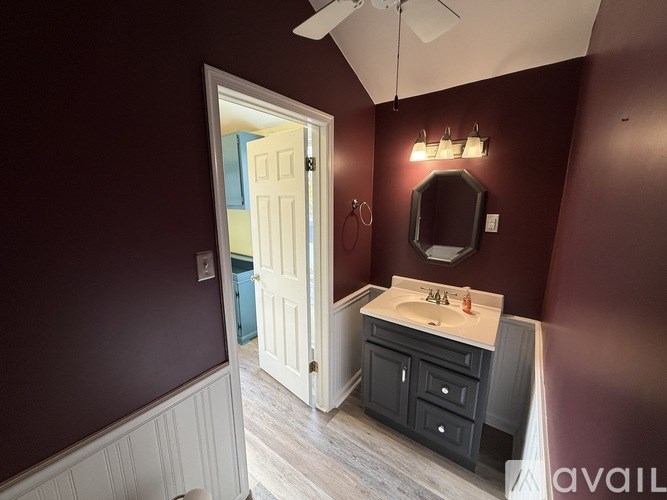 A bathroom with a white door and a white sink with a black cabinet.