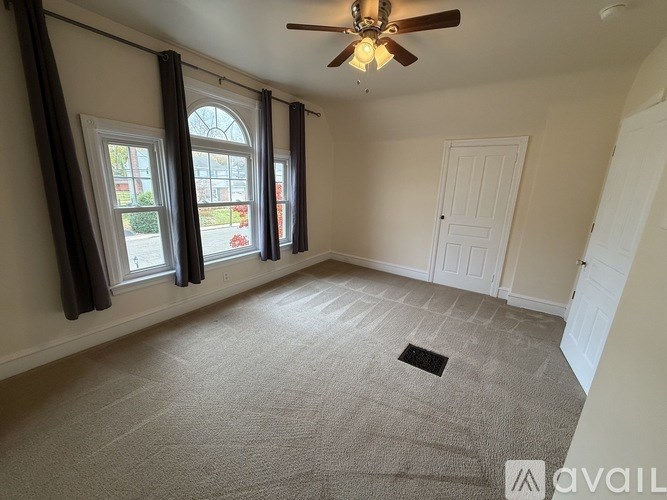 A room with a ceiling fan and carpeted floor.