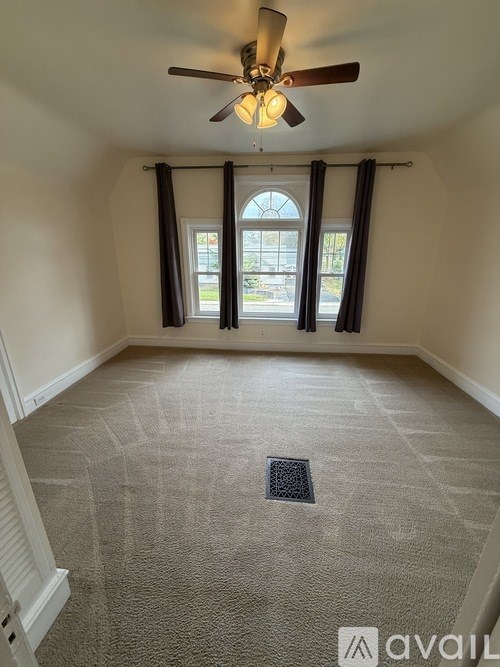 A room with a ceiling fan and carpeted floor.