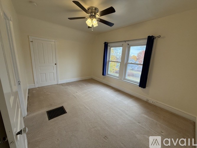 A room with a ceiling fan and a window with a view of trees.