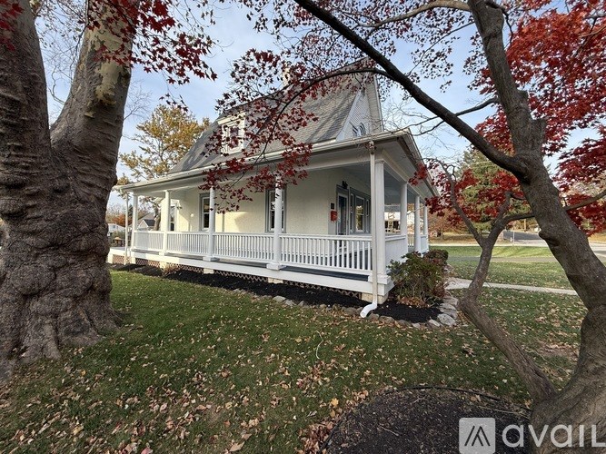 A house with a porch and a tree in front of it.
