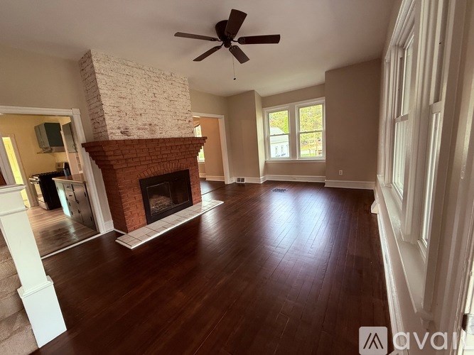A spacious room with a fireplace and wooden floors.