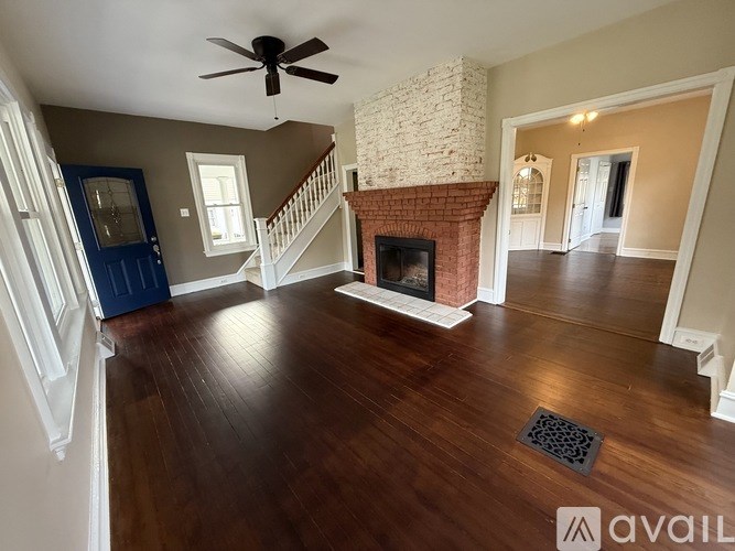 A living room with a fireplace and a ceiling fan.