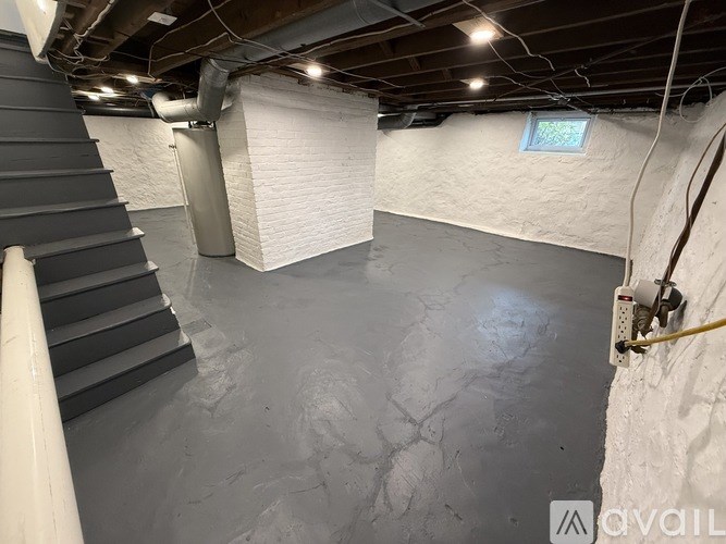 A room with a grey floor and a staircase on the left side.