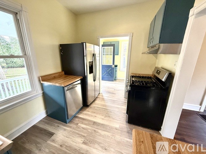 A kitchen with black and blue appliances and wooden floors.