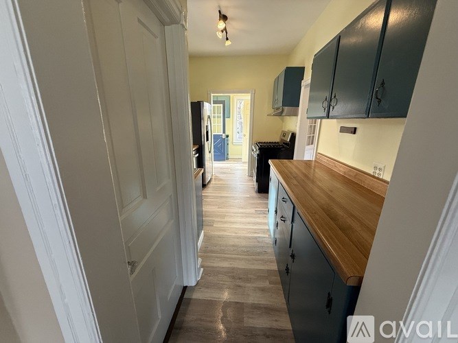 A kitchen with a wooden counter top and green cabinets.
