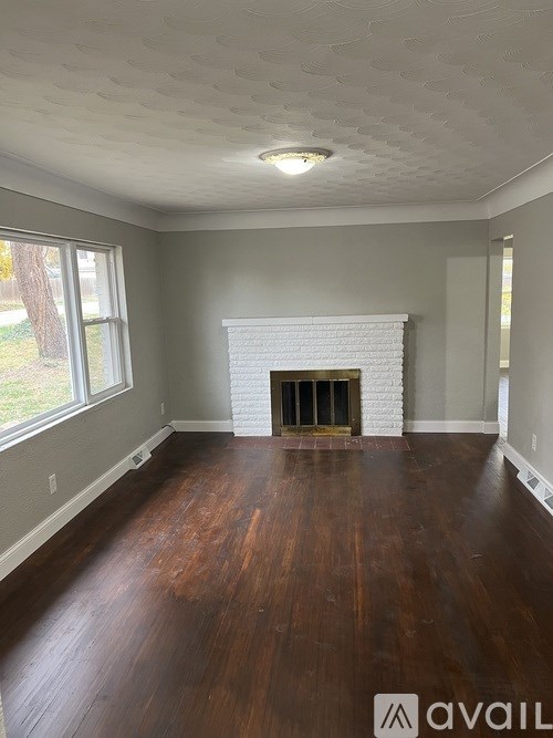 A room with a fireplace and wood flooring.