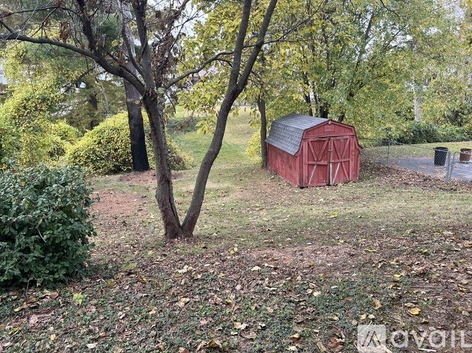 A red barn sits in a field with a tree in front of it.