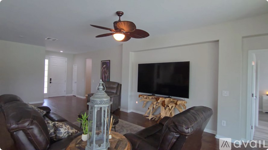 A living room with a brown leather couch and a television.