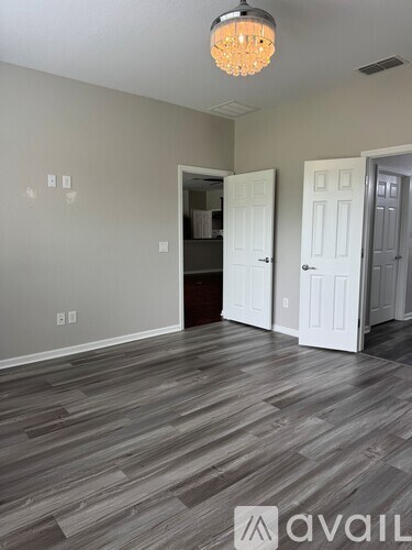 A room with grey flooring and a chandelier hanging from the ceiling.