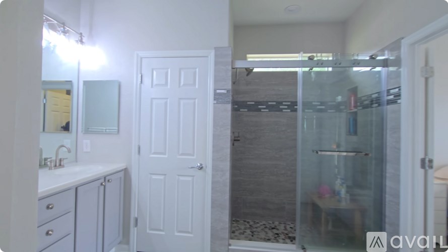 A bathroom with a white door and a glass shower stall.