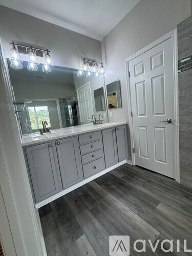 A bathroom with a vanity, mirror, and lighting fixture.