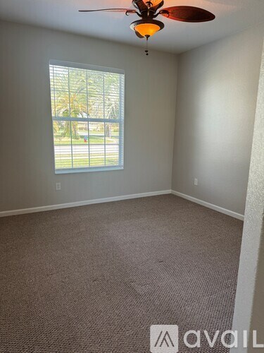 A room with a ceiling fan and a window overlooking a street.