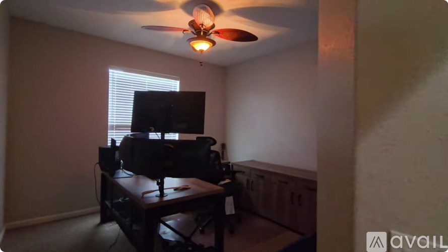 A room with a ceiling fan and a television.