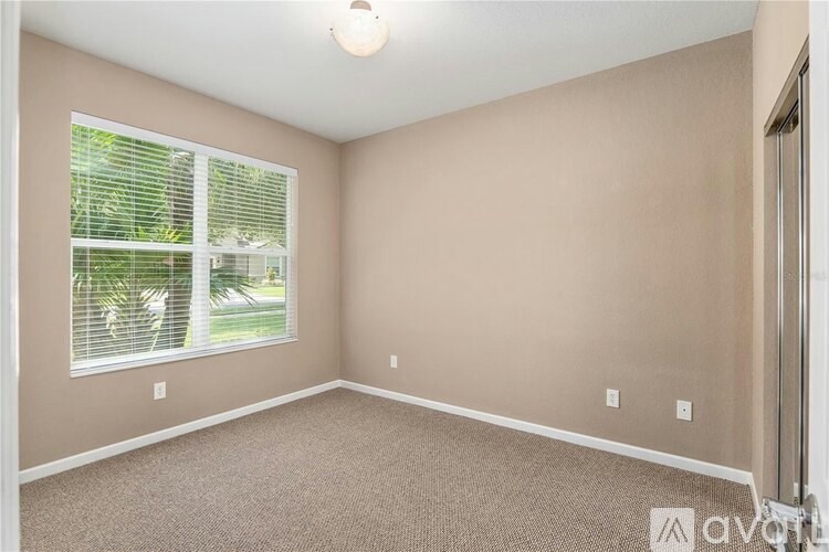 A room with a window and a carpeted floor.